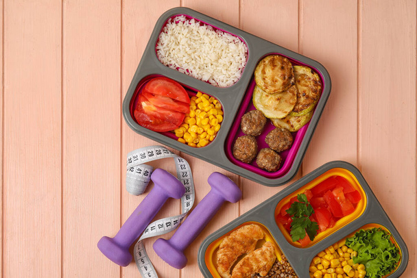 Gefäße mit gesunden Lebensmitteln, Kurzhanteln und Maßband auf farbigem Holzgrund - Foto, Bild