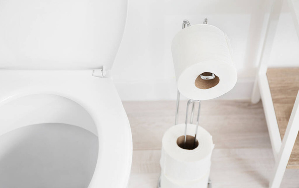 Тримач з паперовими рулонами та унітазом у туалеті
 - Фото, зображення