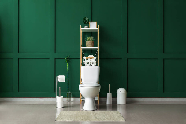 Interior of restroom with toilet bowl, shelving unit and green wall - Photo, Image