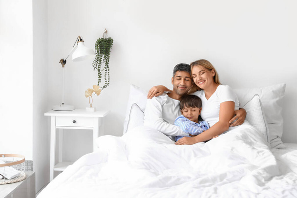 Onnelliset vanhemmat pienen poikansa kanssa makaamassa sängyssä - Valokuva, kuva