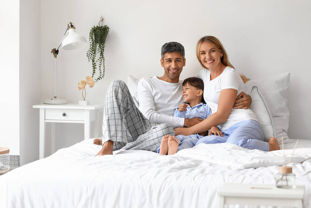 Ευτυχισμένοι γονείς με τον μικρό τους γιο να κάθεται στο κρεβάτι. - Φωτογραφία, εικόνα
