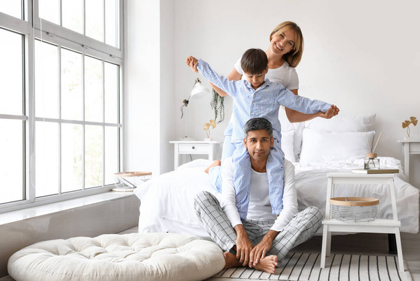 Cute little boy with his parents having fun in bedroom - Photo, image