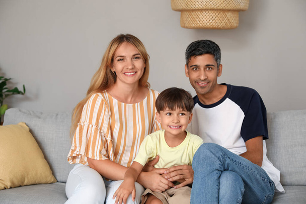 Мальчик с родителями сидит дома на диване - Фото, изображение