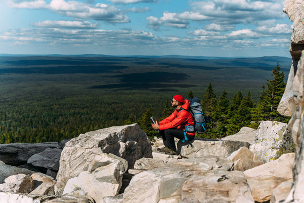 A male tourist is resting after a hard climb up the mountain. A traveler among the Rocky Mountains. A man is a traveler with a backpack among the rocks. Backpacking in the mountains. Copy space - Foto, Bild