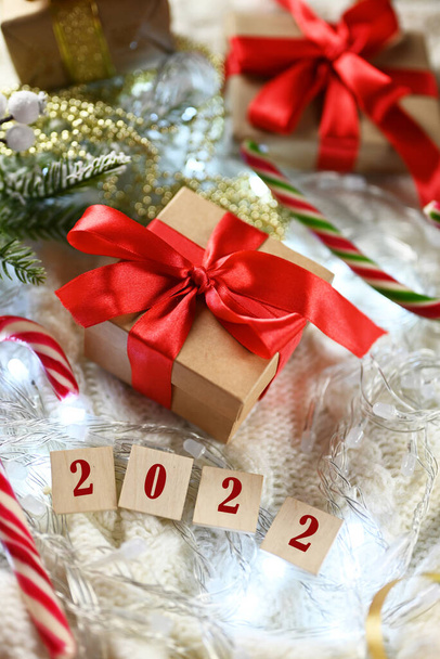 κουτιά δώρου σε πλεκτή κουβέρτα με φιόγκο με γλυκά Αϊ Βασίλη προσωπικό με ξύλινα νούμερα 2022 για το νέο έτος και τα Χριστούγεννα - Φωτογραφία, εικόνα