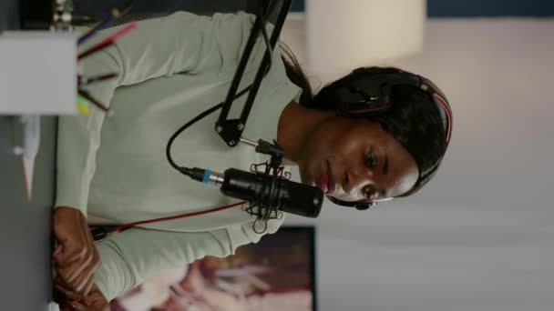 Pionowe wideo: Czarna kobieta gospodarz pokazu online patrząc w laptop rozmowy - Materiał filmowy, wideo