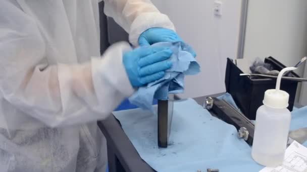 Arbeiter in weißem Schutzanzug und blauen Schutzhandschuhen zur Reinigung von Metallteilen - Filmmaterial, Video