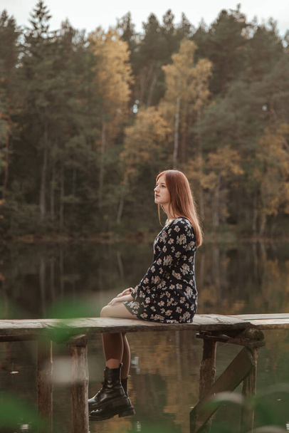 Tyttö istuu puisella sillalla metsäjärven pohjalla.. - Valokuva, kuva