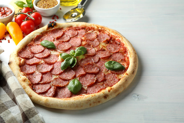 Concept de nourriture savoureuse avec pizza au salami sur fond de bois blanc - Photo, image