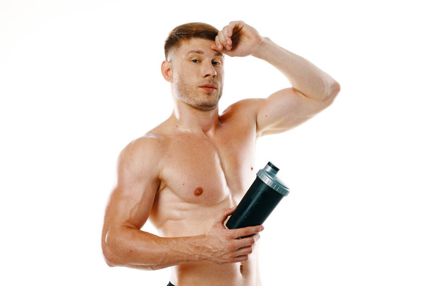 a man an athlete with a pumped-up body drinks from a bottle - Foto, immagini