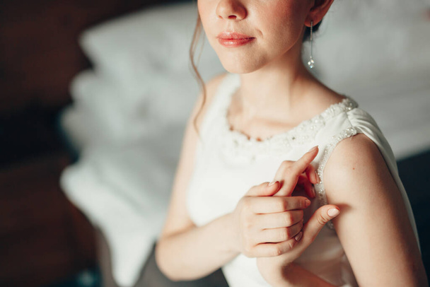 Красивая невеста в белом кружевном платье сложила руки возле плеча. Полупортрет - Фото, изображение