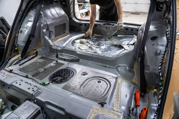 Interior del coche con asientos y tapicería retirados. Preparación para trabajos de reparación o instalación de aislamiento acústico insonorización en SUV moderno - Foto, imagen