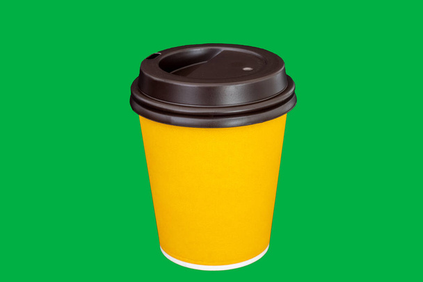 Желтый бумажный кофе или чайная чашка. Картонная чашка на изолированном зеленом фоне - Фото, изображение