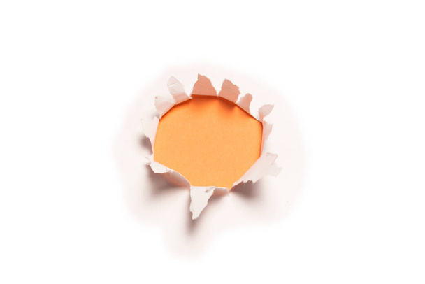 A hole in a white paper on an orange background, copy space.  - Photo, Image