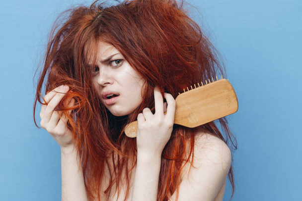 woman with red hair comb care blue background - Foto, Imagen