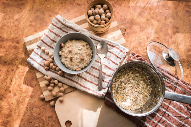 Gezond, voedzaam en voedzaam havermout met hazelnoten in een grijze plaat op het tafelblad. - Foto, afbeelding