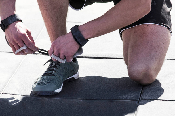 outdoor CrossFit competition,   man an athlete ties a shoelace - Photo, Image