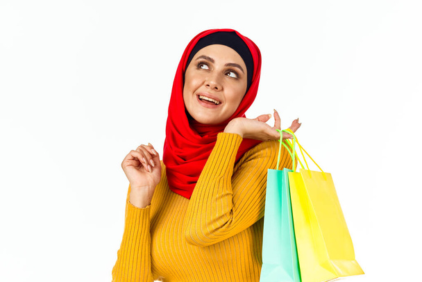 cheerful muslim woman shopping holiday gifts light background - Foto, afbeelding