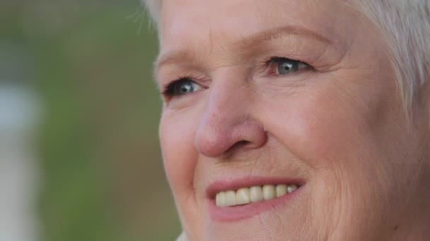 閉じる美しい65歳の女性は脇を見て、広い笑顔白ストレート歯を持っている。アンチエイジング治療、健康手順、歯科クリニックサービス、自然の美しさ、高齢者の肖像コンセプト - 映像、動画