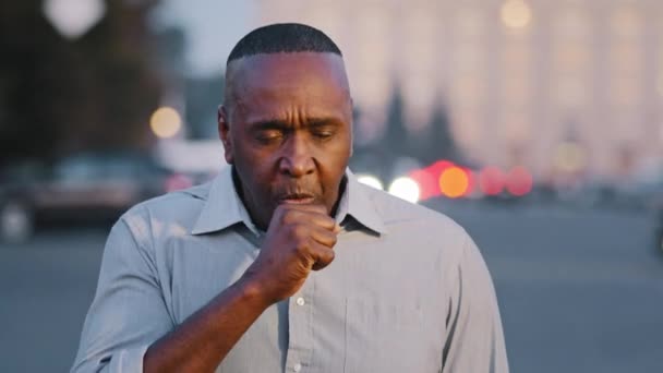 成人したアフリカ系アメリカ人高齢者が屋外で咳をして苦しんでいる気管支炎喘息咳コロナウイルス呼吸器感染の概念の彼の胸の症状を保持する - 映像、動画