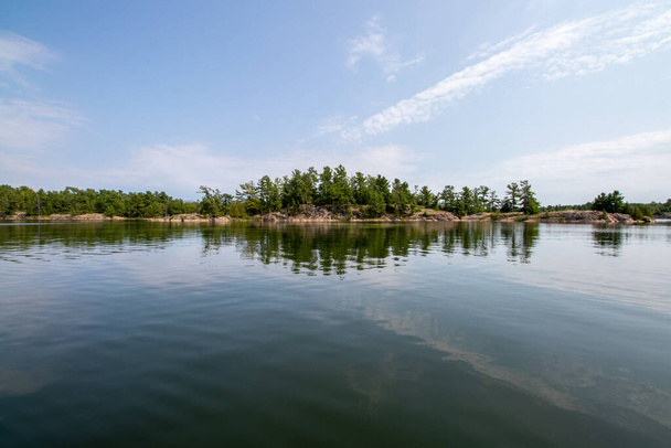 спокойная вода и сосна покрытые острова на побережье в Килларни, Онтарио, Канада в летний день - Фото, изображение