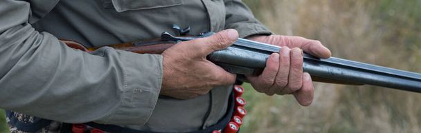 Hombre cazador en camuflaje con un arma durante la caza en busca de aves silvestres o de caza. Temporada de caza de otoño
. - Foto, imagen
