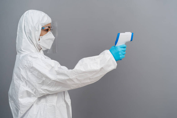 doctor in protective PPE suit scanning with infrared thermometer, IR Thermoscan - 写真・画像