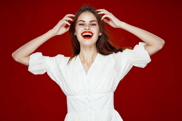 cheerful red-haired woman with red lips white dress red background - Fotó, kép