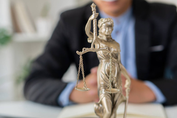 богиня правосуддя з лусками і молотками розміщена перед адвокатом Мейла, який працює над юридичною концепцією ноутбука. Порада щодо правосуддя в офісі юриста - Фото, зображення