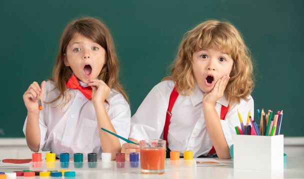 Excited school surprised children drawing a colorful pictures with pencil crayons in classroom. Portrait of amazed excited pupils enjoying art and craft lesson. Childhood learning, kids artistics - Fotoğraf, Görsel