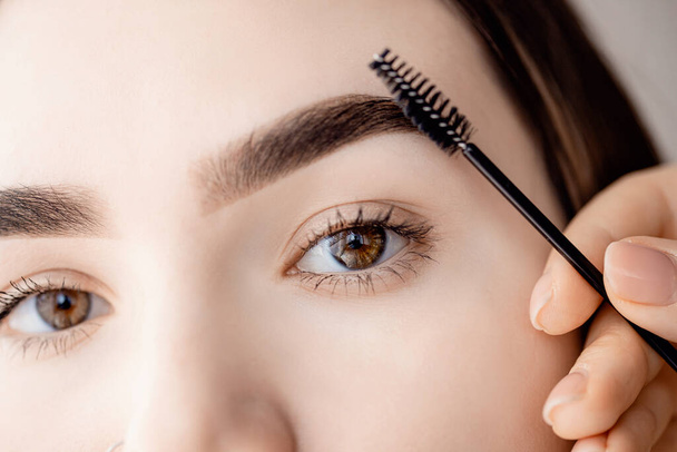 Master tweezers depilation of eyebrow hair in women, brow correction with comb - Фото, изображение