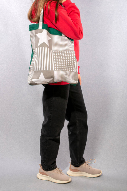 Bir kız elinde doğal kumaştan yapılmış tekrar kullanılabilir bir Eko Poşet tutuyor. - Fotoğraf, Görsel