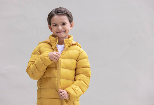 冬の準備をしている黄色の服を着た可愛い男の子. - 写真・画像