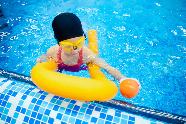 A szemüveges kislány megtanul úszni a medencével. Sárga tészta. - Fotó, kép