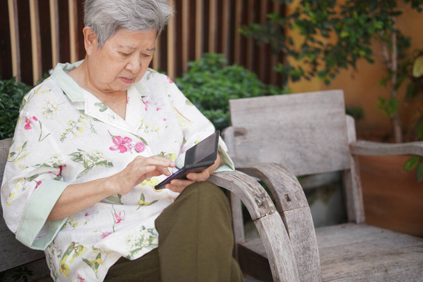 ázsiai idős nő idős férfi használ mobiltelefon mobiltelefon szabadtéri. érett nyugdíjas életmód - Fotó, kép
