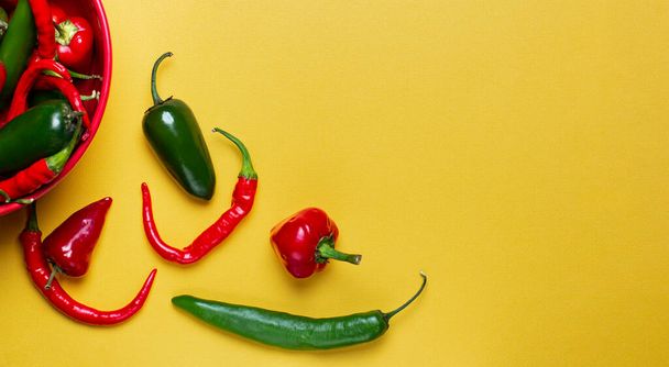 Yellow pastel background with hot peppers, top view, place for text, copy space - Photo, Image