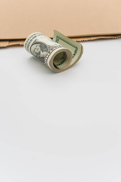 rolled up US dollar banknotes and brown paper on a white tabletop with text space - Photo, image