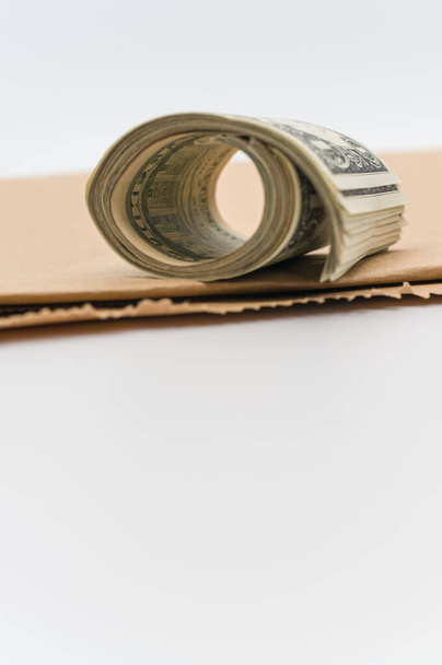 rolled up US dollar banknotes and brown paper on a white tabletop with text space - Фото, зображення