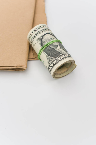 rolled up US dollar banknotes and brown paper on a white tabletop with text space - Photo, image