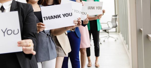 Group of businesspeople join together greeting and hold thank you word for sign of thankfulness to someone in modern office. Idea for good teamwork feeling declaration and support for colleagues. - Photo, Image