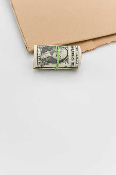 rolled up US dollar banknotes and brown paper on a white tabletop with text space - Fotó, kép