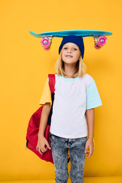 scolaretta con uno skateboard sulla sua testa isolato sfondo - Foto, immagini