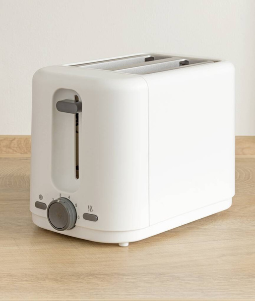 Elektrikli ekmek kızartma makinesi ahşap mutfak tezgahında duruyor. - Fotoğraf, Görsel