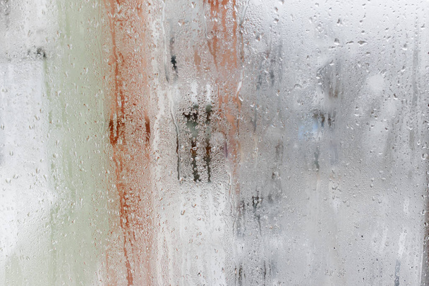 Condensation sur la fenêtre en verre transparent, gouttes d'eau, pluie. Verre de fenêtre avec humidité de l'air élevée. Contexte de la condensation naturelle de l'eau - Photo, image