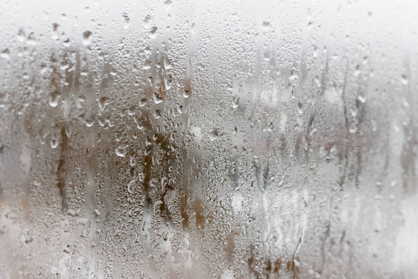 Kondenzáció a tiszta üvegablakon, vízcseppek, eső. Ablaküveg magas páratartalommal. A természetes vízlecsapódás háttere - Fotó, kép