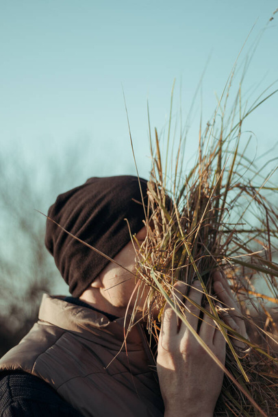 the man enjoys the smell of hay, covers his face with grass and inhales. - Foto, Bild