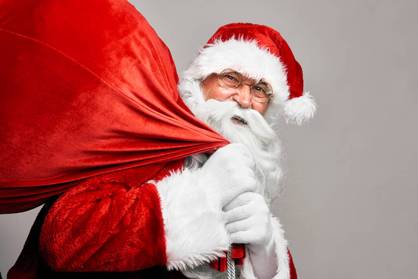 Porträt des kaukasischen Weihnachtsmannes mit einem Sack voller Geschenke  - Foto, Bild