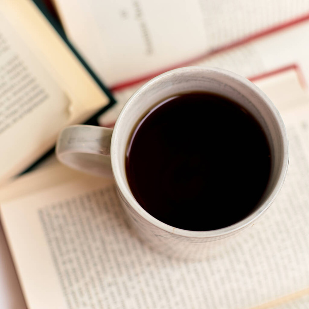 Open books and coffee mug on a book, top view - Fotó, kép