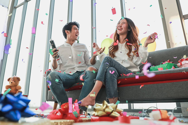 Приємні молоді азіатські пари насолоджуються святкуванням нового року, граючи барвисті паперові спалахи у вітальні, прикрашені скринькою з подарунками, вишуканою кулькою для веселої вечірки в прекрасний день зимового сезону. - Фото, зображення