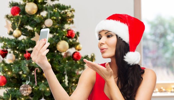 woman in santa hat taking selfie by smartphone - Zdjęcie, obraz